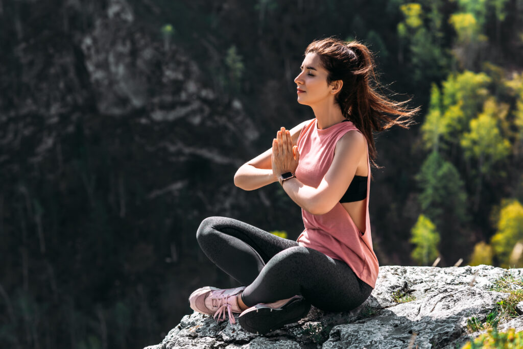 Attractive woman doing yoga. Healthy lifestyle. The concentration of the body. Woman doing yoga in the mountains. Girl doing yoga at sunrise. Woman meditates in nature. Meditation in the mountains Achtsamkeit Stressbewältigung Coping Strategie