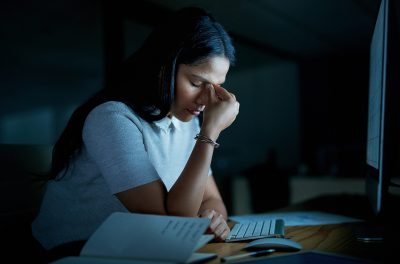 Shot of a young businesswoman looking stressed while using a computer during a late night at work.